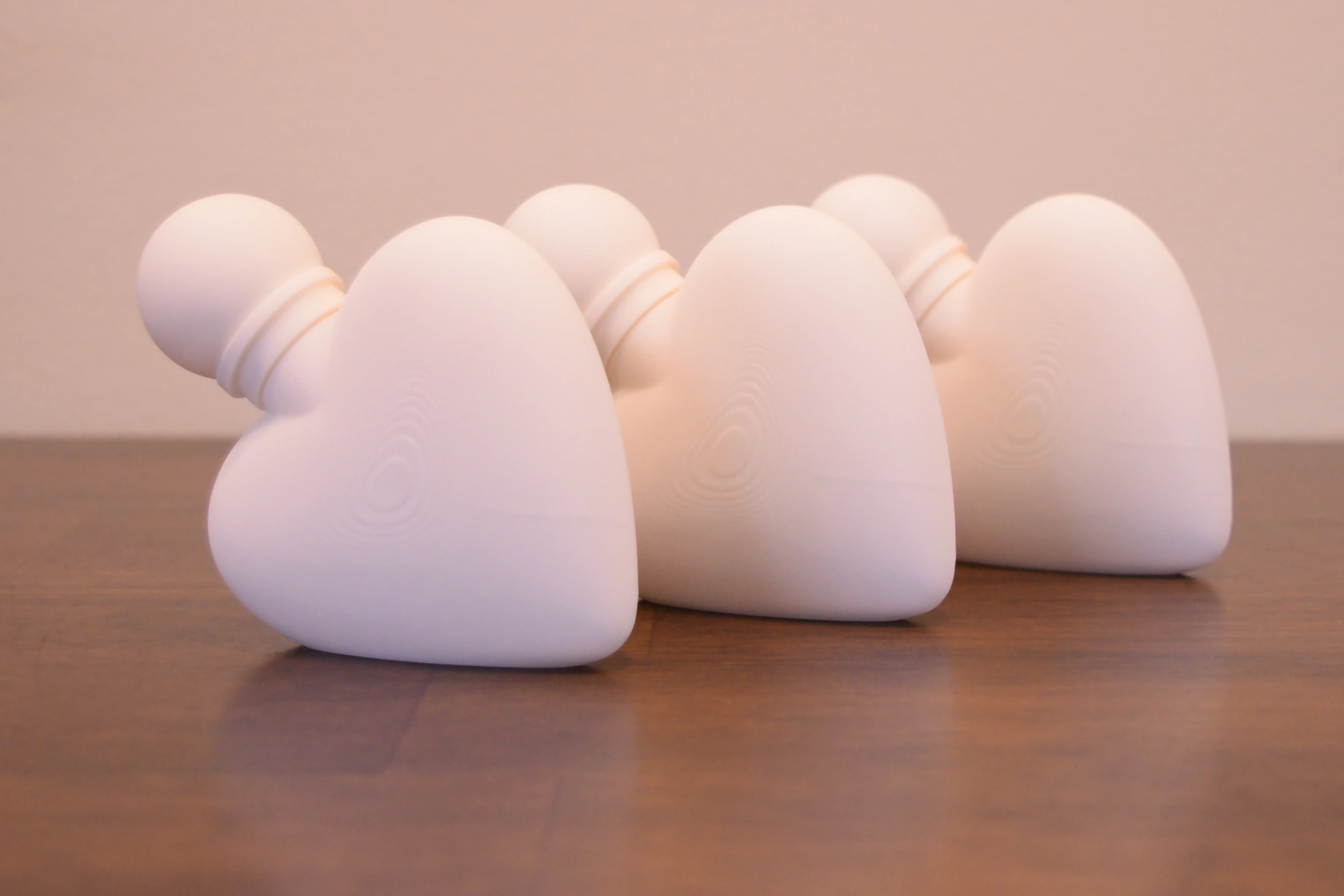 Three matte white FDM-printed perfume bottles arranged on a wood table